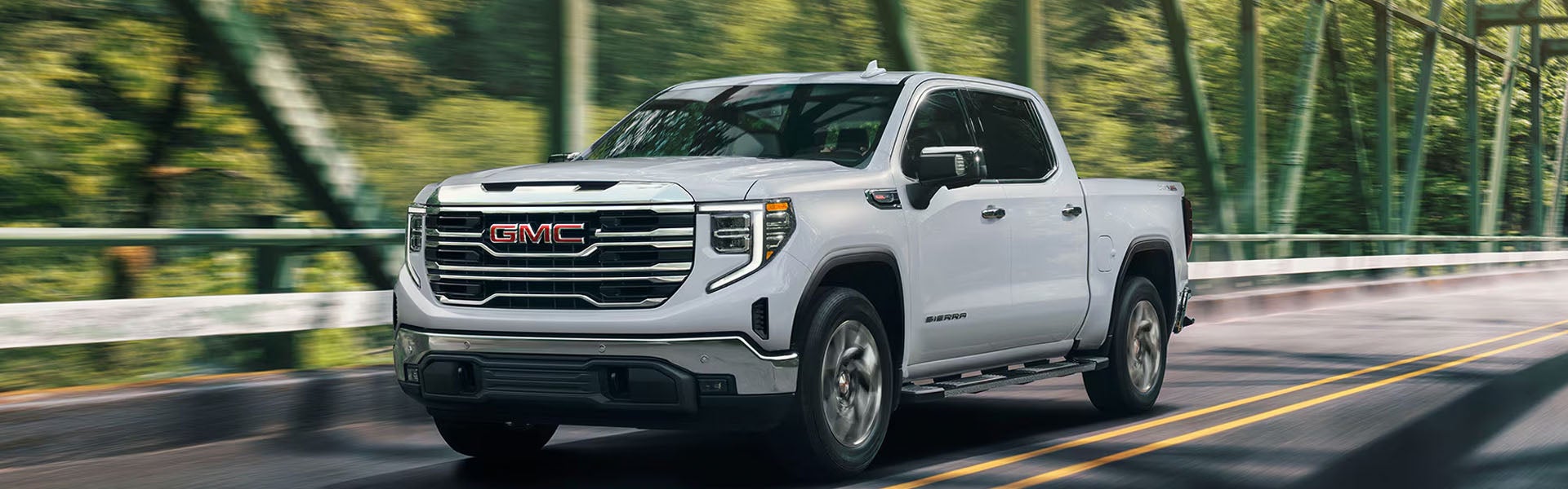 2026 GMC Sierra 1500 pickup truck driving through a rugged outdoor landscape