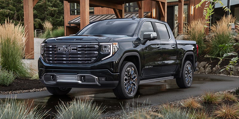 Black 2026 GMC Sierra 1500 parked outside a modern home.